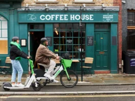 Two Lime riders using an electric scooter and e-bike outside a coffee shop