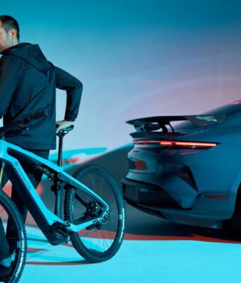 Porsche Is Shutting Down Its Performance E-Bike Division A rider on a Porsche eBike beside a Porsche Taycan Turbo GT