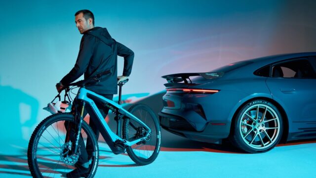 Porsche eBike official newsroom image A rider on a Porsche eBike beside a Porsche Taycan Turbo GT