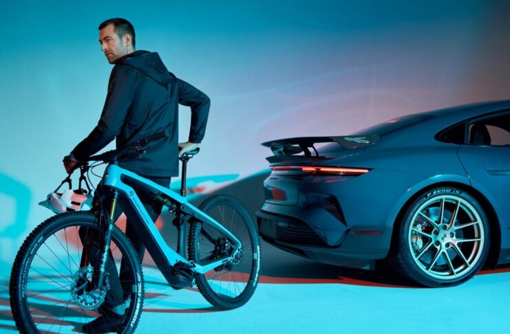 A rider on a Porsche eBike beside a Porsche Taycan Turbo GT